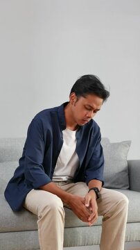 Anxiety Asian man sitting on sofa in home with stress, trauma or stimming with overthinking. Mental health, panic attack