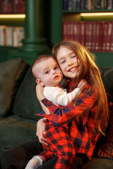 Two children share a smile while sitting on a green sofa in a cozy room