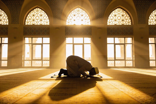 Silhouette of Muslim Man Praying and Prostrating in Grand Mosque During Ramadan