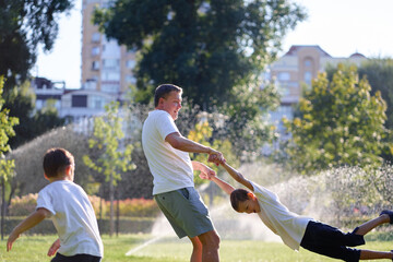 Fototapeta premium Father and Sons Playing Joyfully Outdoors on a Sunny Day