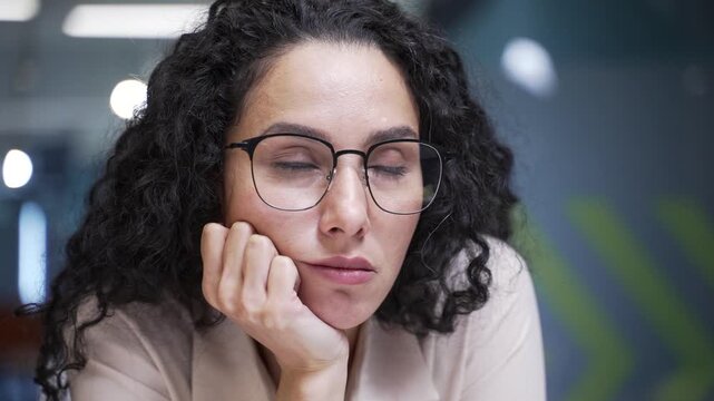 Sad businesswoman is bored sitting at workplace in business office. Female employee has depression and personal problems suffering from mental pain, worries, feels despair, disappointment. Close up