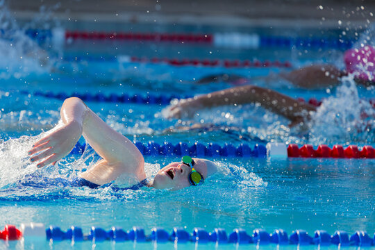 Girl racing/ training competitive freestyle at a public swimming pool