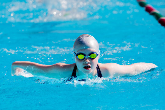 Girl racing/ training competitive butterfly at a public swimming pool
