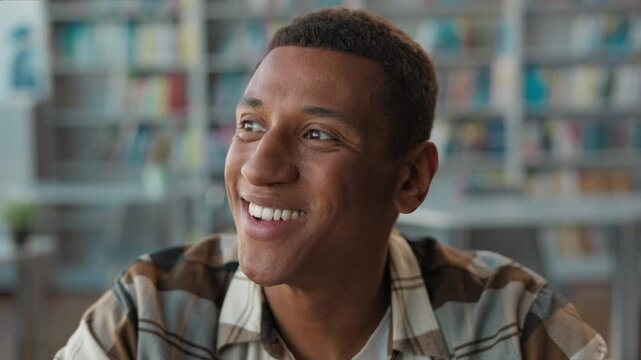 Happy inspired African American man student having genius idea in library smiling male thinking pointing finger gesture brainstorming guy touching chin imagination insight study learning inspiration