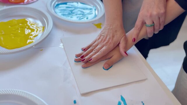 Child and teacher make handprint painting as a Mother&rsquo;s Day gift