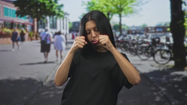 Woman pulls her cheeks with fists and pouts on a busy street by parked bicycles and trees; playful defiance.
