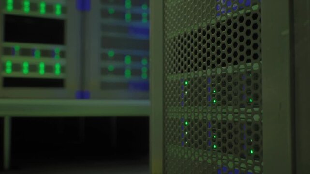 Close up rack with soft green bokeh, front panel sensors and status indicators blurred in foreground, distant illuminated server bank in background, ambient
