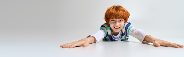 Naklejka premium Stylish young boy joyfully reaching out in a playful moment of fun and creativity