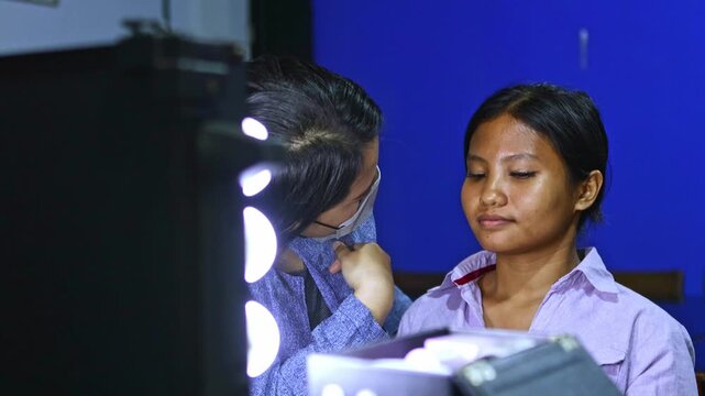 Professional makeup artist applying foundation on asian model