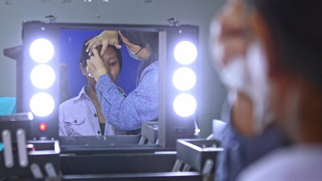 Professional makeup artist applying foundation on an Asian model's face
