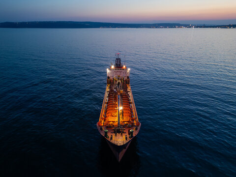 Aerial View of Industrial Tanker Ship at Sea During Sunset with City Lights