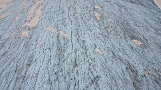 Aerial view of a glacier with snow and ice formations creating a textured landscape, juxtaposed with rocky terrain, Obergoms, Valais, Switzerland.