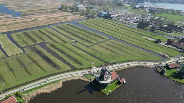 Aerial view of the iconic Zaanse Schans Windmill, a vivid contrast of red rooftops against the tranquil waters, Zaandam, Noord-Holland, Netherlands.