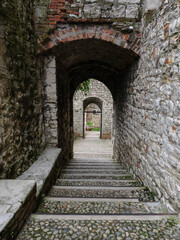 Obraz premium Stone Cobblestone Steps Under Successive Brick Arches In A Narrow Medieval Fortification Passage, Brescia, Italy