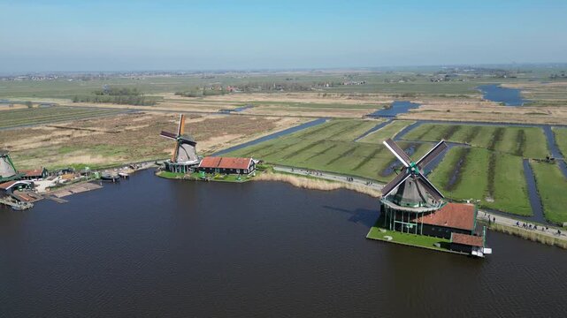 Aerial view of the historic Zaanse Schans windmills standing proudly amidst the waterways and green fields, a vivid contrast of rustic charm, Zaandam, Noord-Holland, Netherlands.