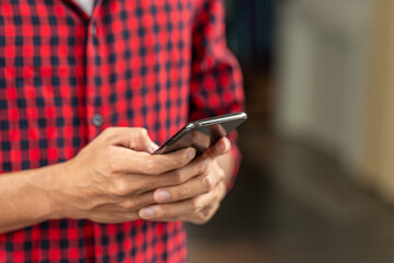 Fototapeta premium Close up of man using smartphone and typing on mobile device