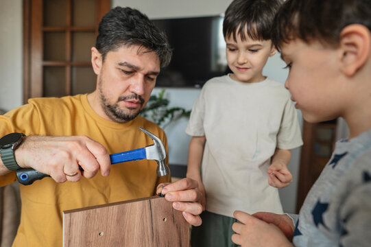 Father teaching children how to assemble furniture at home