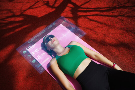 Person relaxing on exercise mat outdoors using virtual glasses and fitness tracking