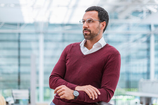 Thoughtful business portrait in modern office with glasses and sweater