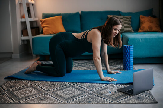 Prenatal yoga exercise with laptop in living room for back pain relief