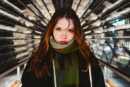 Confident youth with bold gaze in futuristic urban architecture at night