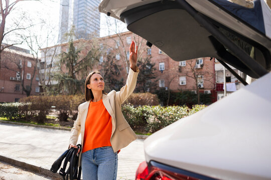 Woman charging electric car outdoors in urban setting
