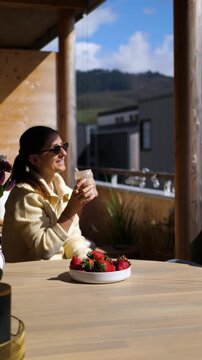 Young Women Cheers with Iced Coffee on Sunny Balcony, Spring Vibes