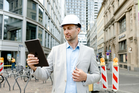 Architect with construction helmet using tablet on Frankfurt city street