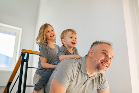 Father playing indoors with children in modern home enjoying family time
