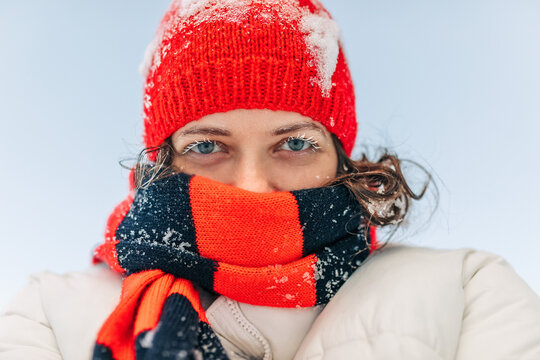 Woman with red knit hat and striped scarf in extreme winter cold