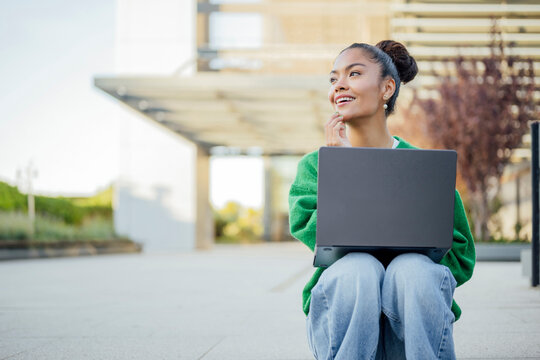 Student with laptop thinking and studying outdoors on campus