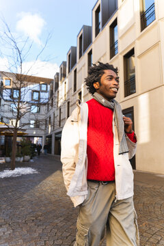 Smiling man exploring winter city street in casual outfit