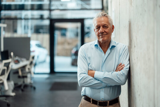 Boss standing confidently in modern office with arms crossed