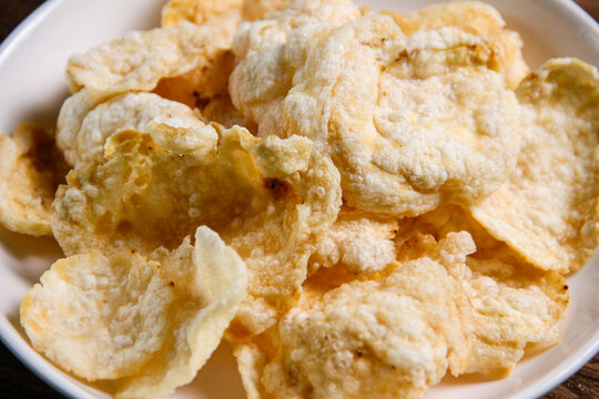 Close up of Melinjo nut chips on a white ceramic plate, made from Gnemon seed (Gnetum gnemon). Indonesian melinjo crackers. Suitable for snacks or topping dishes