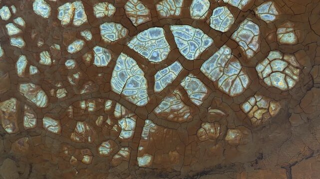 Aerial view of cracked earth with reddish-brown soil and pale blue mineral patterns in Minas de Riotinto, Andalusia, Spain.
