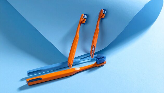Orange Toothbrushes with Blue Bristles on Light Blue Background