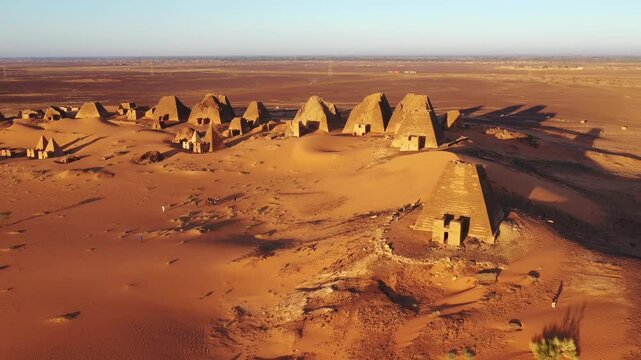 Aerial view of ancient pyramids standing tall against the desolate desert landscape, the contrast of light and shadow creating a surreal scene, Kabushiya, Sudan.