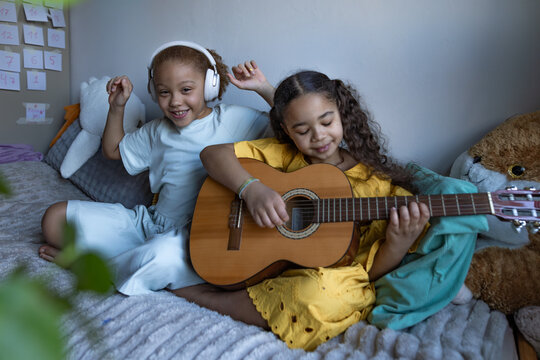 Girls playing guitar and listening to music together indoors