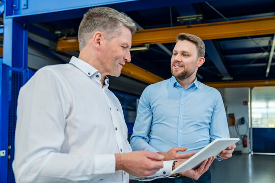 Business employees meeting with digital tablet in production hall