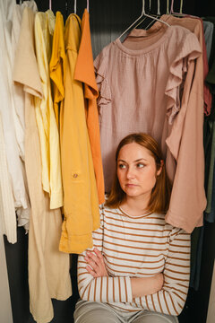Woman feeling stressed and overwhelmed by outfit choices in wardrobe