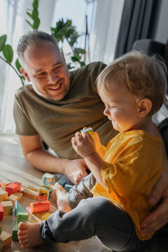 Father and child playing with wooden blocks indoors