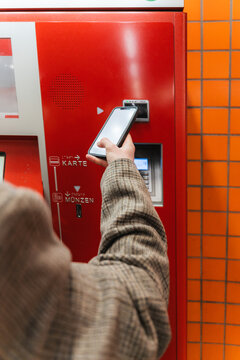 Person using smartphone for contactless payment at ticket machine