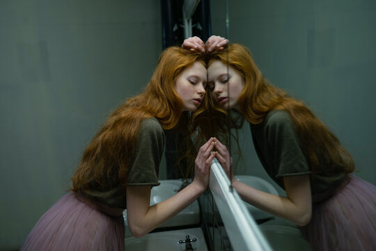 Red haired woman with freckles leaning on mirror in old building