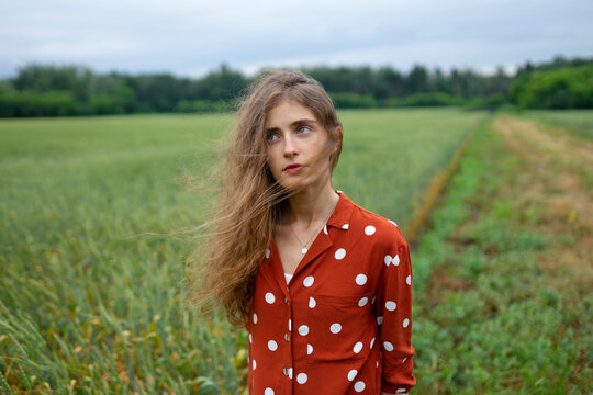 Woman in red polka-dot blouse smiling in wheat field outdoors
