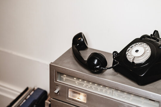 Vintage black rotary telephone and retro radio in interior setting