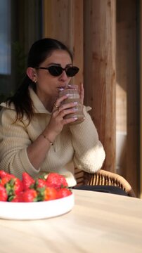 Young Women Cheers with Iced Coffee on Sunny Balcony, Spring Vibes