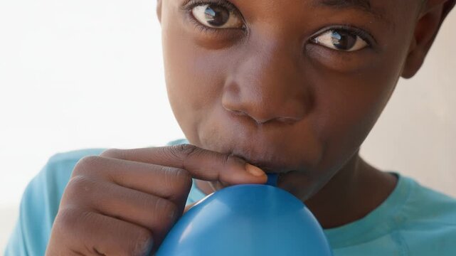 Child happily plays. Joyful kid with colorful balloon. Excited young boy inflates vibrant balloons joyfully. Cheerful child smiles widely while enjoying lively balloon inflation process