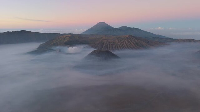 Aerial view of volcanoes shrouded in ethereal clouds, creating a mystical landscape of peaks and valleys, Bromo Tengger Semeru National Park, East Java, Indonesia.