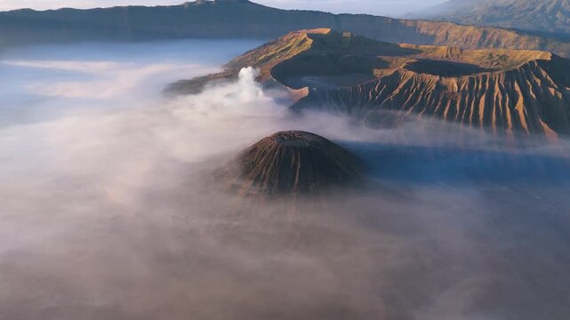 Aerial view of Mount Bromo's peaks piercing through a thick blanket of clouds in a surreal landscape, Bromo Tengger Semeru National Park, East Java, Indonesia.