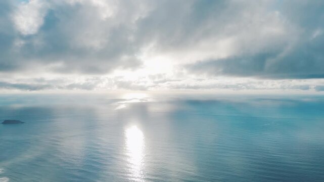 Aerial high altitude view of the Atlantic Ocean surface during calm sunrise with clouds running in the sky